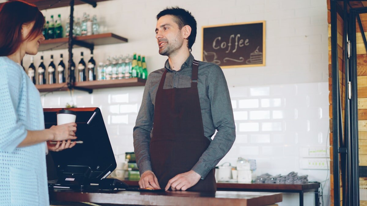 A customer holding a smartphone at a cafe counter