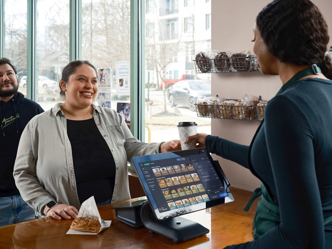 Barista hands coffee to smiling customer at counter.