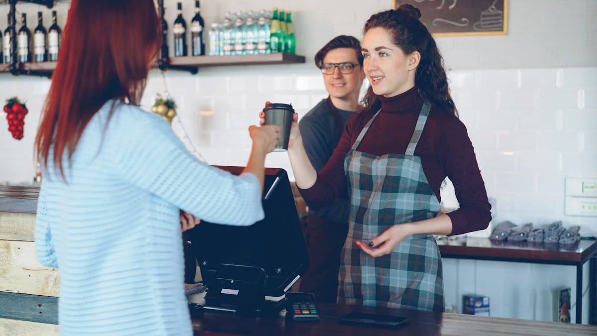 A customer holding a smartphone at a cafe counter